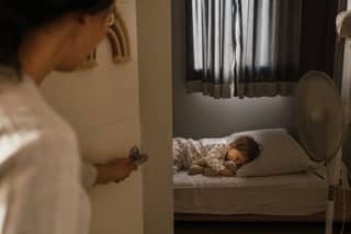 Niño pequeño durmiendo la siesta en habitación fresca y oscura durante un día caluroso de agosto