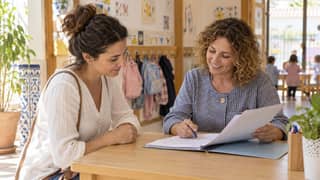 Una madre revisa documentación con una profesional en la recepción de una escuela infantil