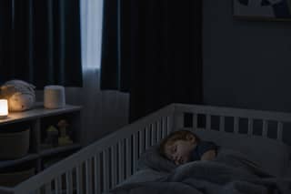 Niño pequeño durmiendo la siesta en habitación oscura y fresca con cortinas opacas en verano