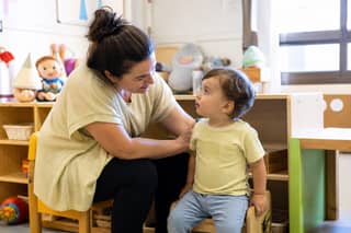 Educadora acompañando a un peque en el aula durante la primera mañana de adaptación en escuela infantil