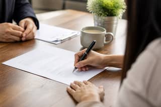 Padre firmando el contrato de matrícula de la guardería en un escritorio