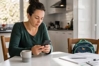 Madre revisando el parte diario de la guardería en el móvil durante el desayuno del lunes por la mañana