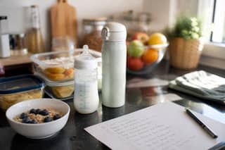 Desayuno preparado en la cocina para el lunes con fruta cortada, cereales y biberón, domingo por la noche antes de empezar la adaptación en la guardería