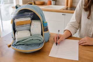 Checklist de material de guardería junto a una mochila abierta con mudas organizadas, botella de agua y muda en bolsa separada