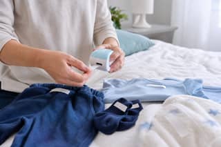 Progenitor etiquetando ropa de recambio y calcetines pequeños para la guardería sobre una cama