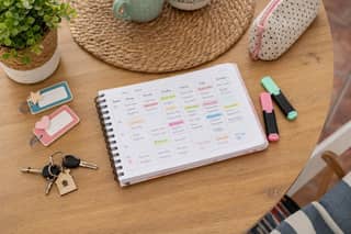 Planificador semanal en una mesa con llaves y material escolar para organizar mañanas de colegio y guardería