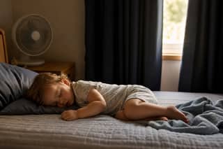 Niño durmiendo la siesta en habitación fresca y oscura durante el verano