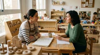 Una madre conversa con una educadora infantil en el aula para acordar apoyos prácticos