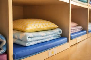 Colchoneta, manta y almohada etiquetados en el armario de siesta de una guardería