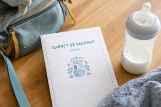 Carnet de vacunas junto a una mochila infantil, documentos necesarios antes de empezar guardería